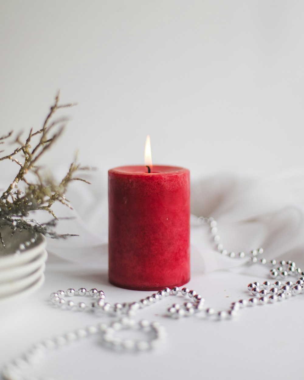 red pillar candle on white table cloth