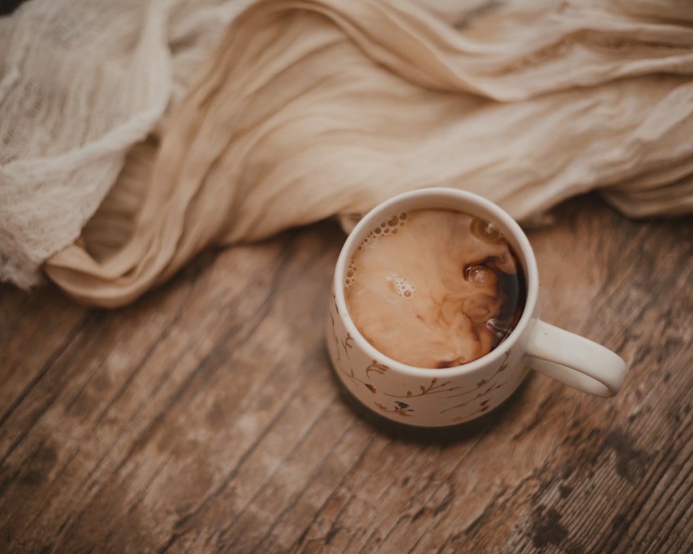 white ceramic mug on white textile