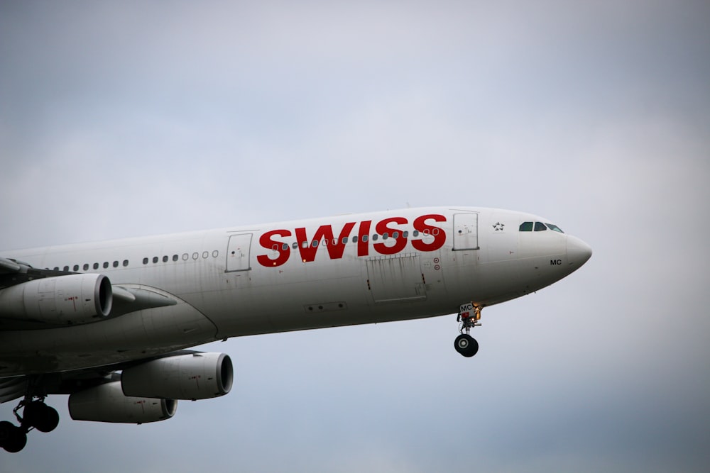 white and red air plane under white clouds during daytime