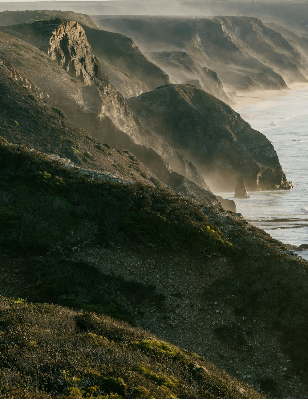 green and brown mountain beside sea during daytime