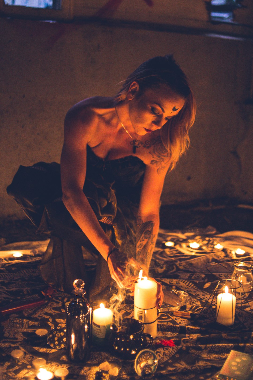 woman in black brassiere sitting on floor with lighted candles