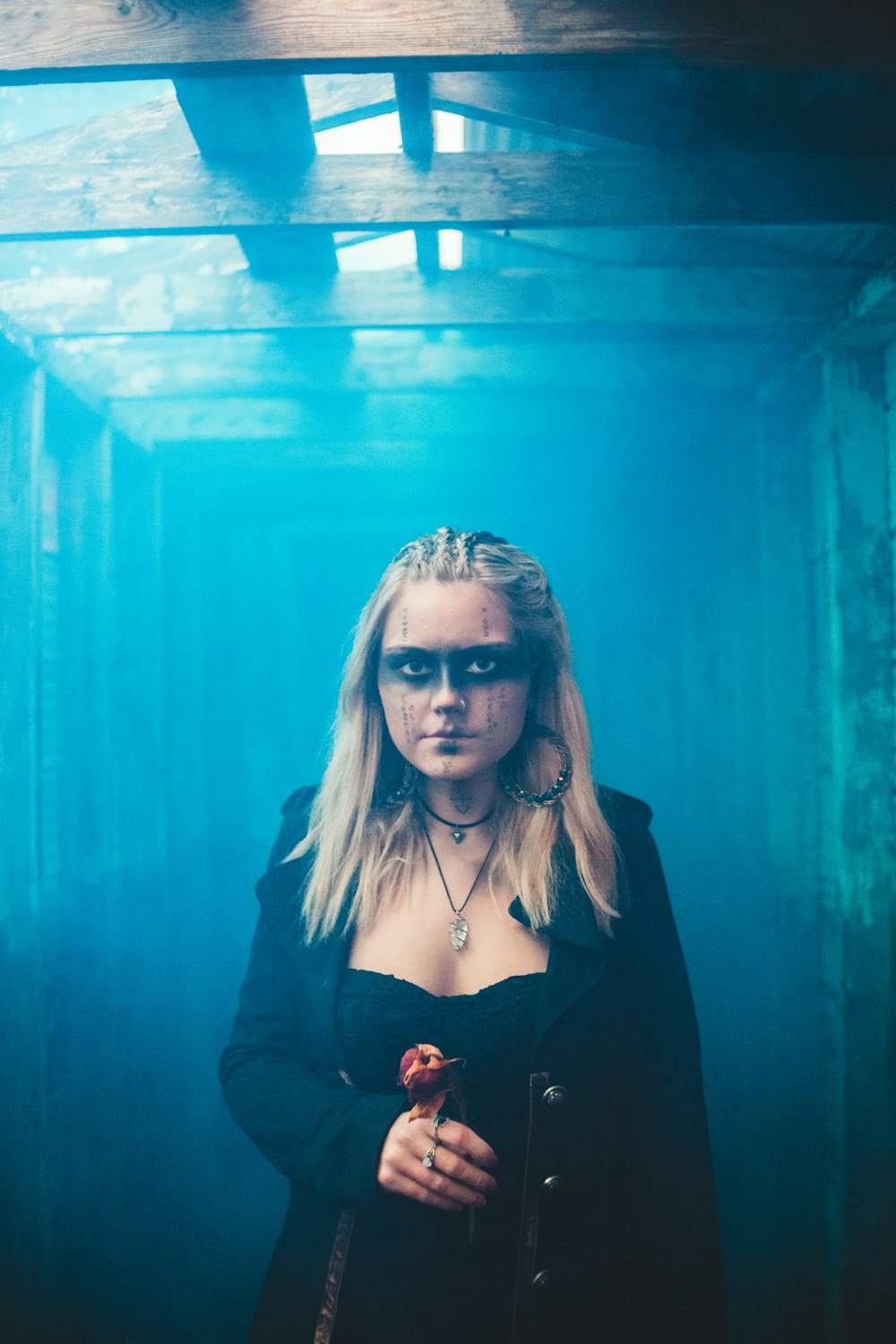 woman in black jacket standing beside blue wall