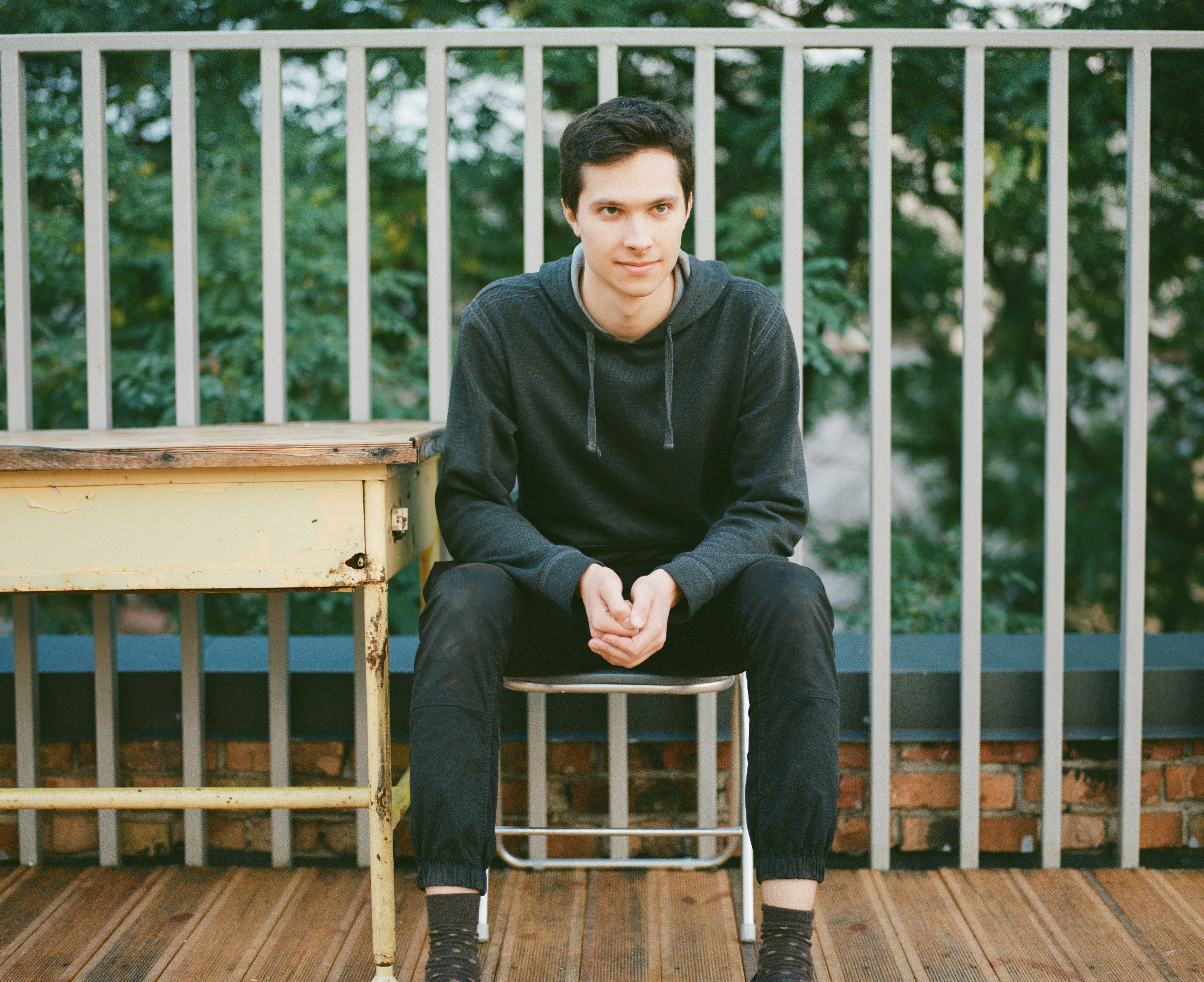 man in black sweater sitting on brown wooden chair