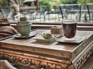 A rustic wooden table with a slice of homemade cake, a glass of fresh juice, and a cup of coffee, all beautifully arranged.