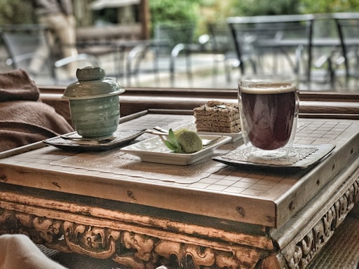 A rustic wooden table with a slice of homemade cake, a glass of fresh juice, and a cup of coffee, all beautifully arranged.