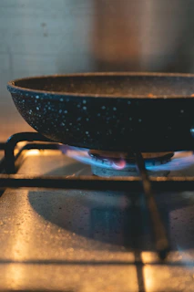 Ceramic frying pan sizzling with a golden omelette on a gas burner