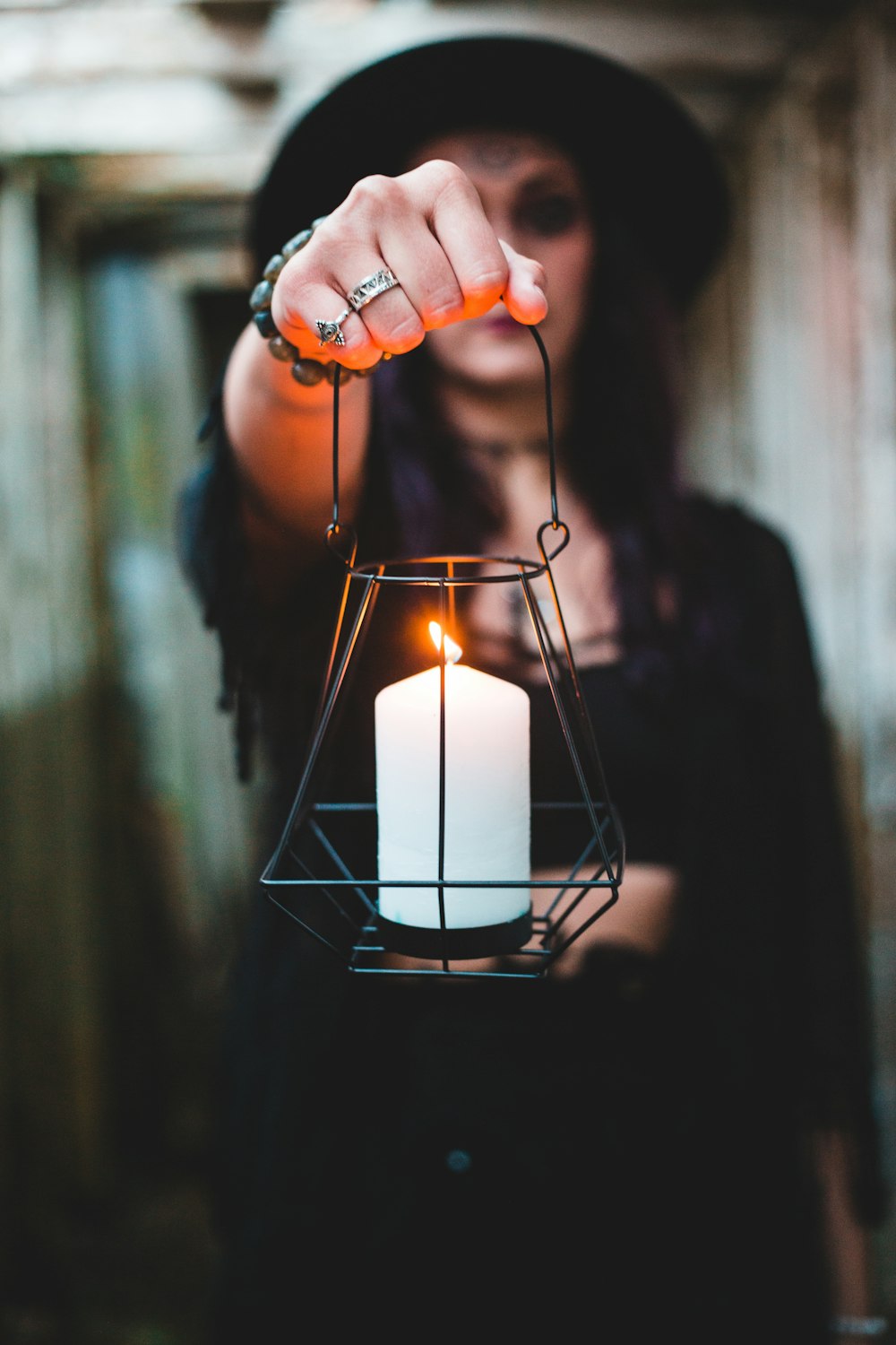 person holding lighted candle in front of black metal frame