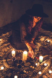 woman in black leather jacket wearing brown hat sitting on brown rock