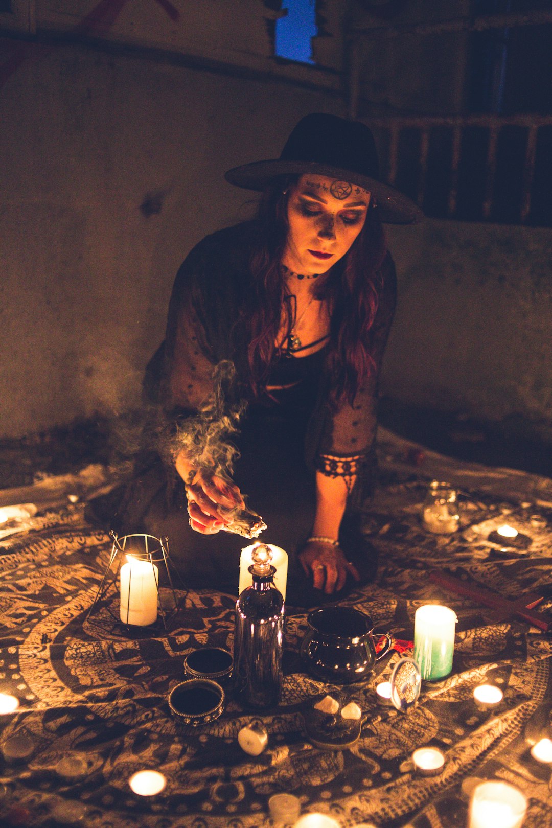 woman in black hat sitting beside lighted candles