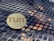 A wooden circular token with the word 'TUIT' engraved on it lies on a metal grid table with a geometric pattern.