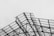 An intricate steel structure is prominently featured, with crisscrossing metal beams supporting transparent panels. The geometric pattern of the frame creates an industrial and modern aesthetic against a plain, overcast sky.