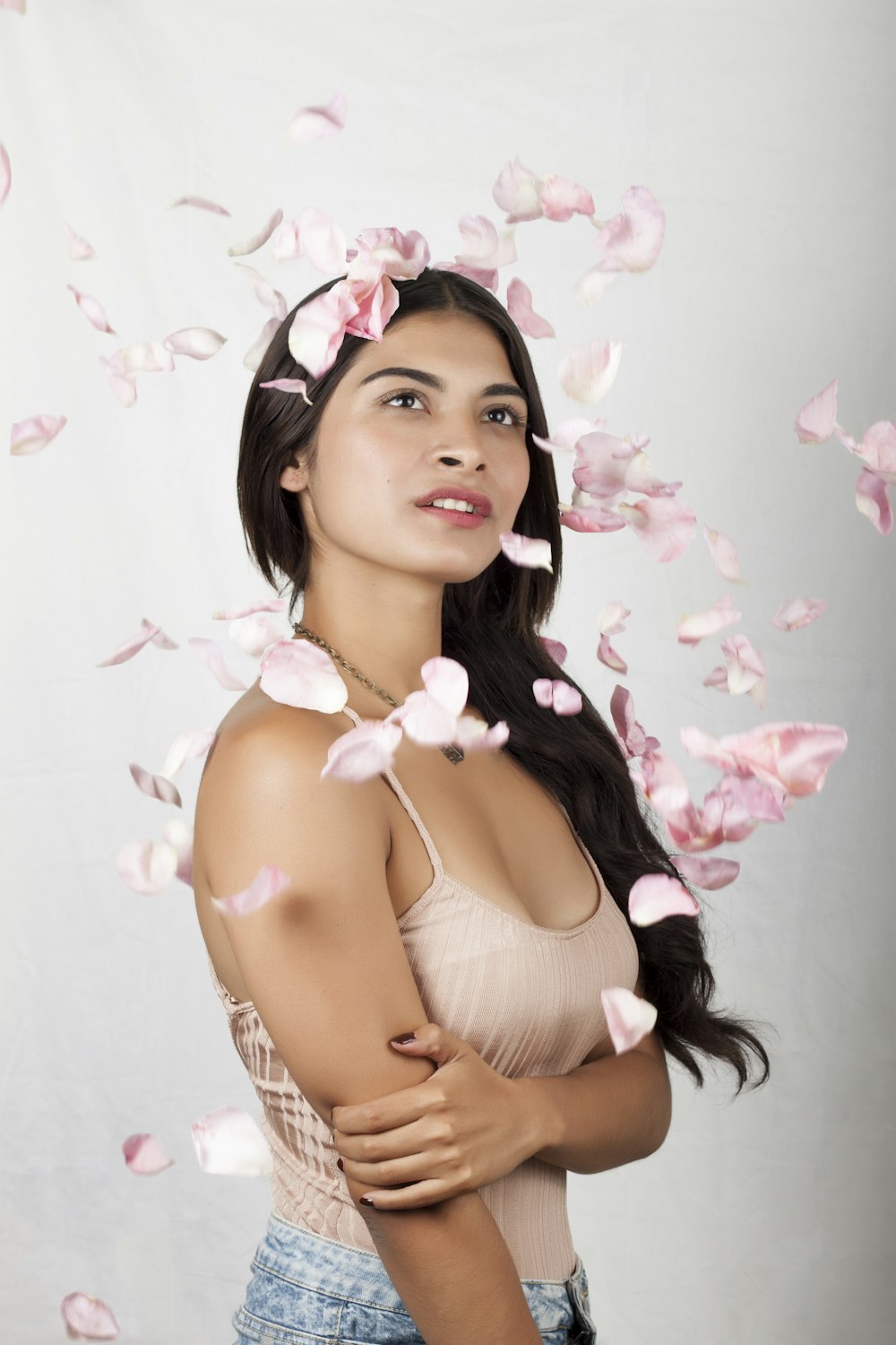 woman in white halter top with pink flower petals on her head