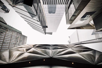 Close-up of modern skyscrapers with reflective windows and geometric patterns against a bright sky.