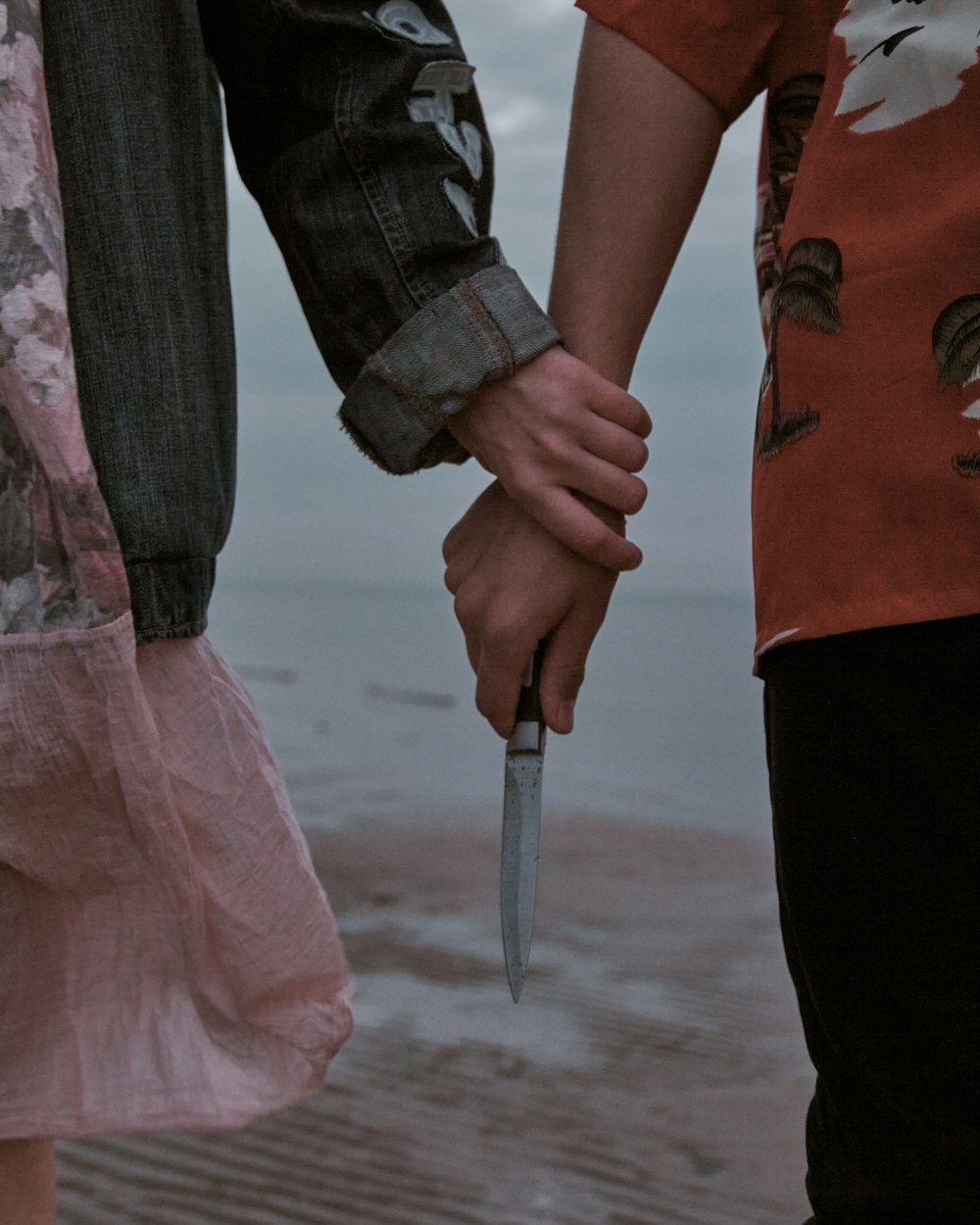 man in red and black crew neck t-shirt holding hands with woman in pink dress