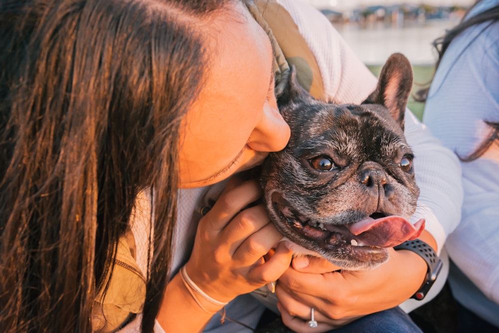 woman in orange shirt holding black pug