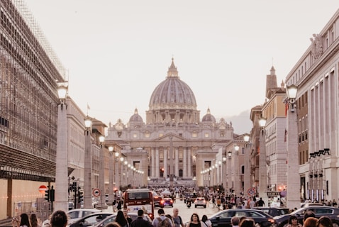 carros e pedestres em rua em frente à basílica de São Pedro, no Vaticano