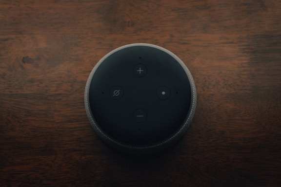 Amazon Echo Dot preto sobre mesa de madeira marrom