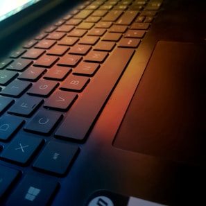 Close-up of a sleek laptop keyboard with glowing keys in a cozy workspace.