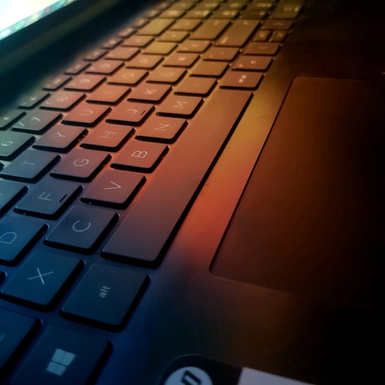 Close-up of a laptop keyboard with hands typing in a cozy room