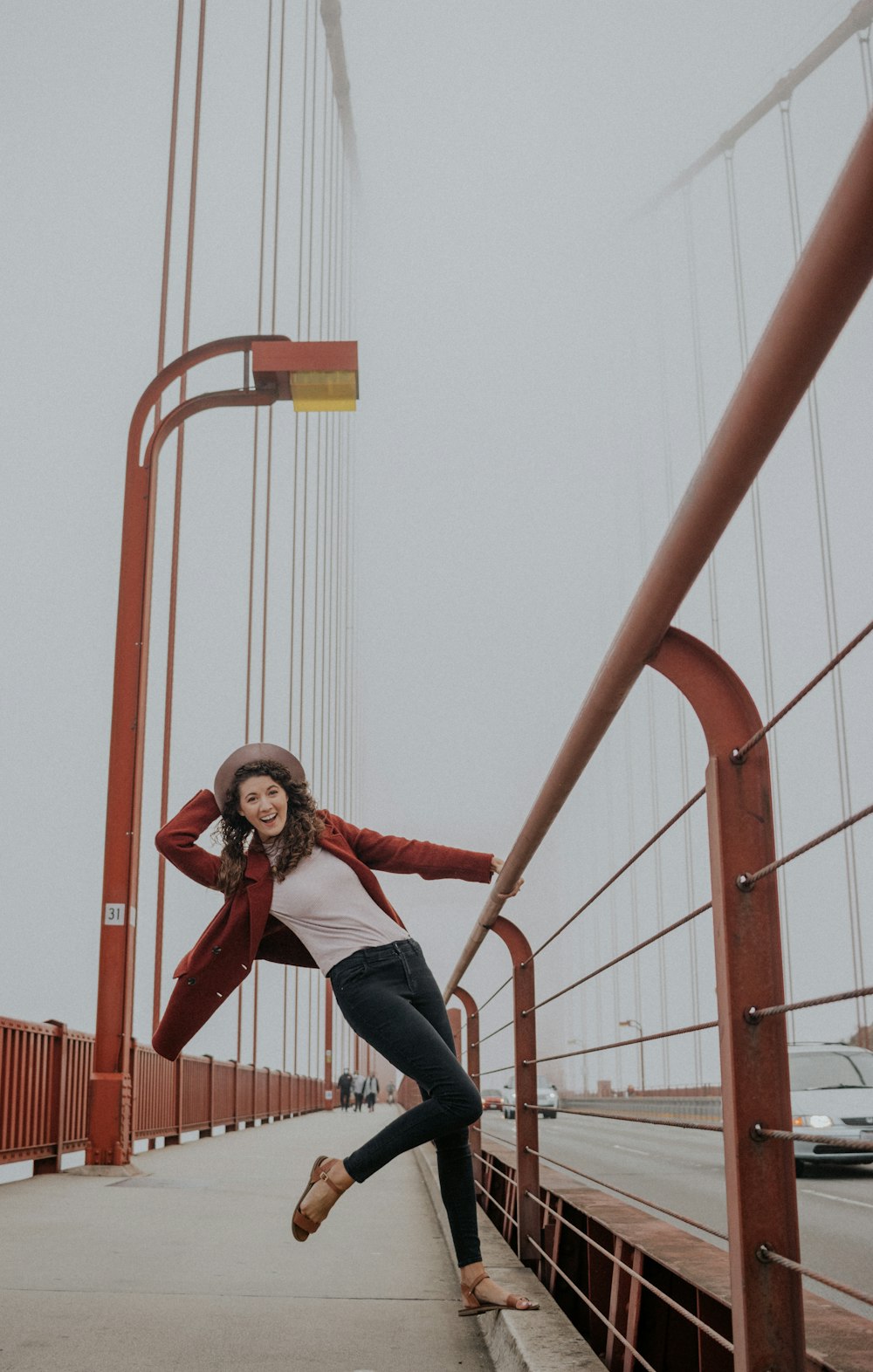 woman in purple jacket and blue denim jeans sitting on yellow metal bar