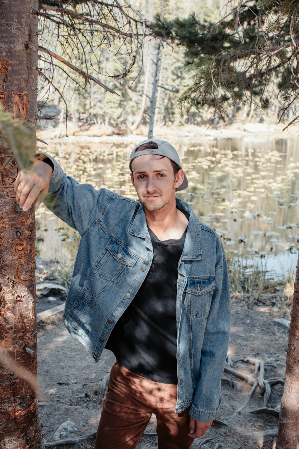 man in blue denim jacket holding wood