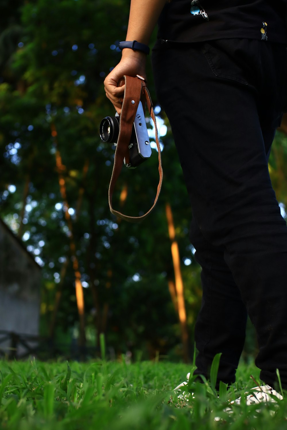 person in black pants holding black and white dslr camera