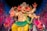A colorful statue of a multi-armed deity adorned with jewelry and elaborate clothing, set against a vibrant, starry background. The deity has the face of an elephant and a small symbol on its palm, with various accessories enhancing its divine appearance.