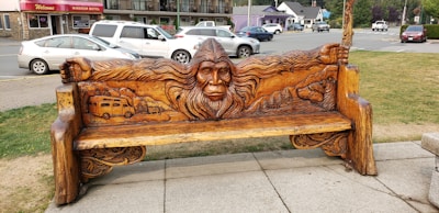 A close-up of a wooden Sasquatch carving nestled among autumn leaves.