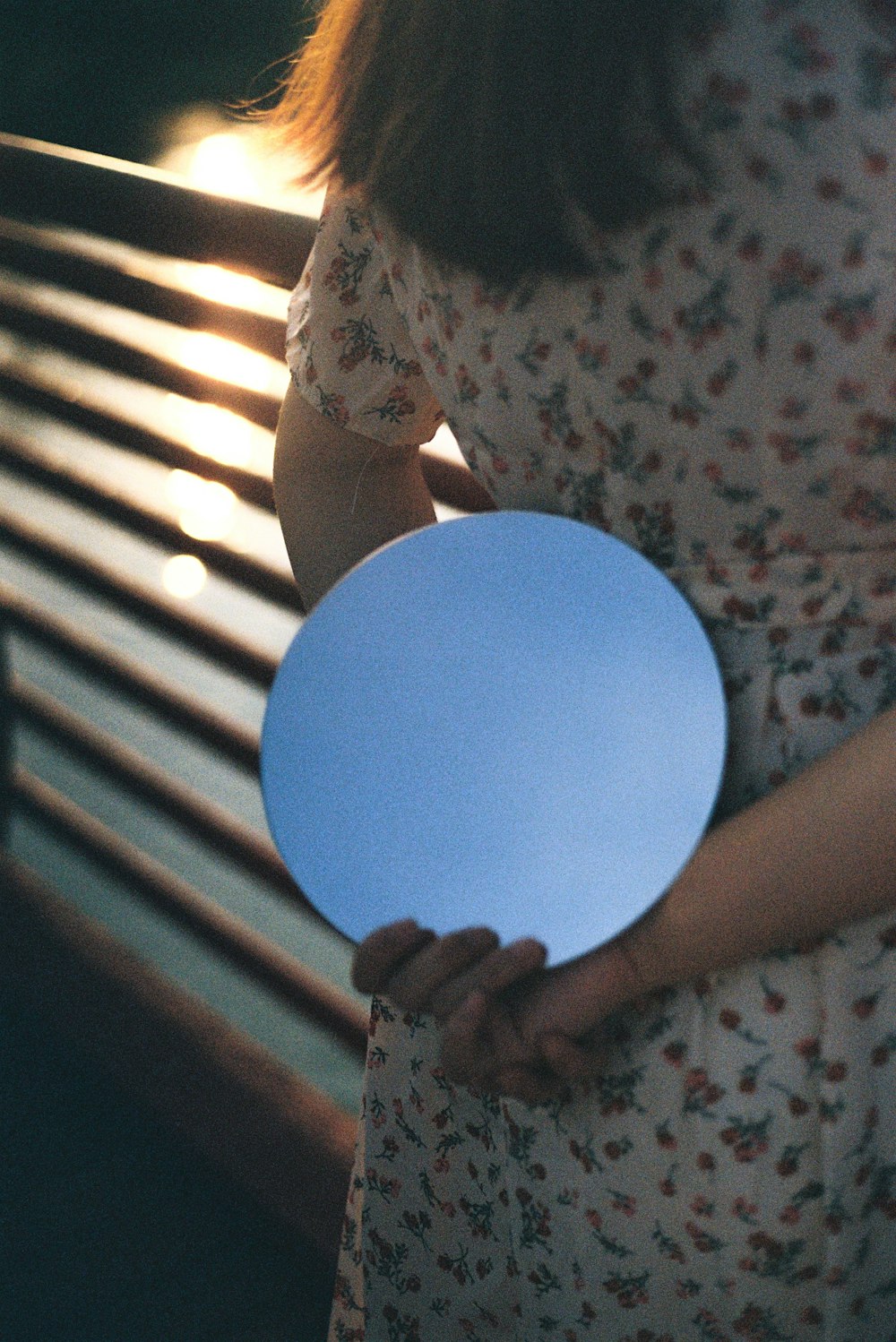 woman in white and green floral shirt holding blue balloon