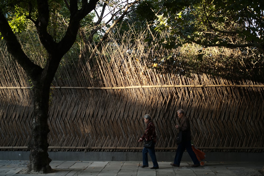 2 women standing near brown wooden fence during daytime