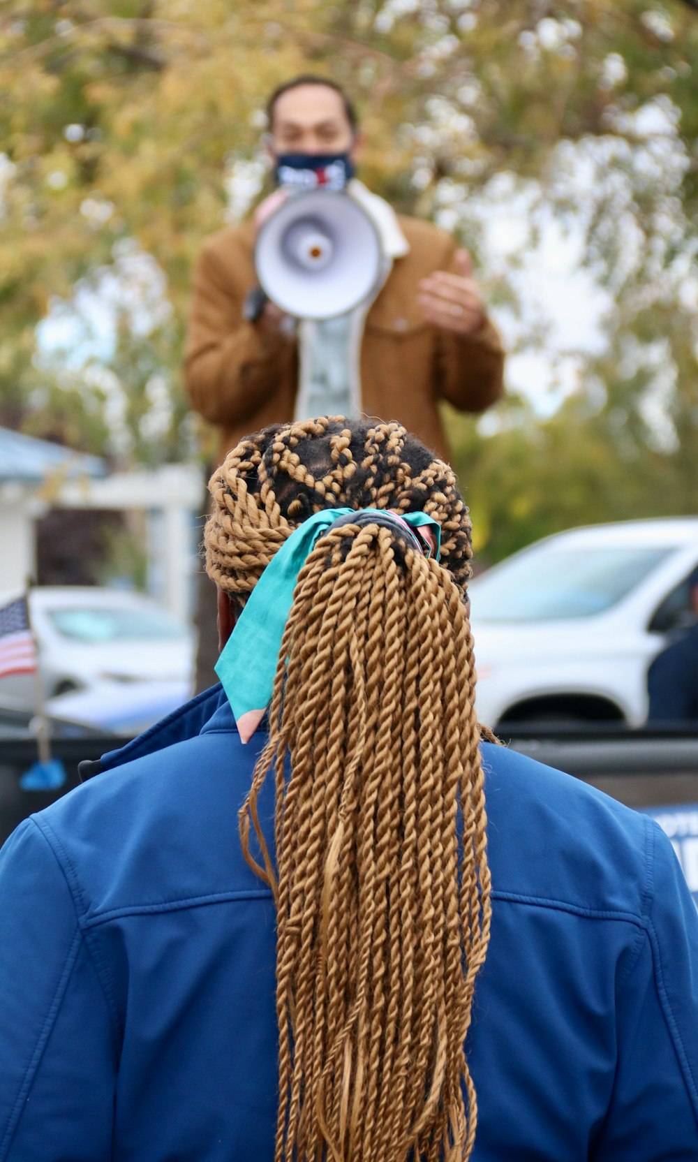 donna in camicia blu a maniche lunghe che tiene la sciarpa a maglia marrone e nera