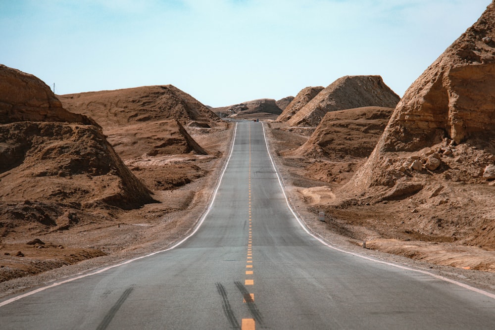 gray concrete road near brown mountain during daytime