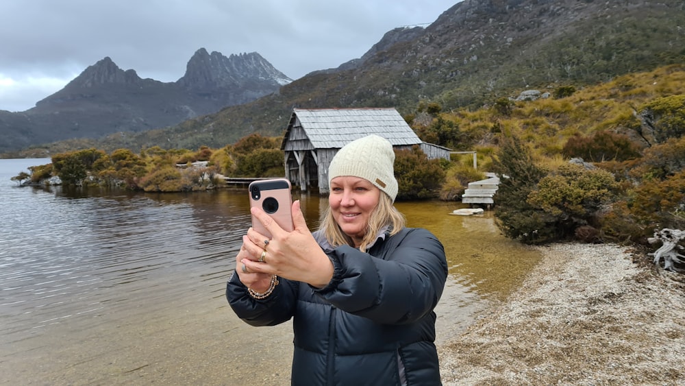 Frau in schwarzer Jacke mit schwarzem Smartphone