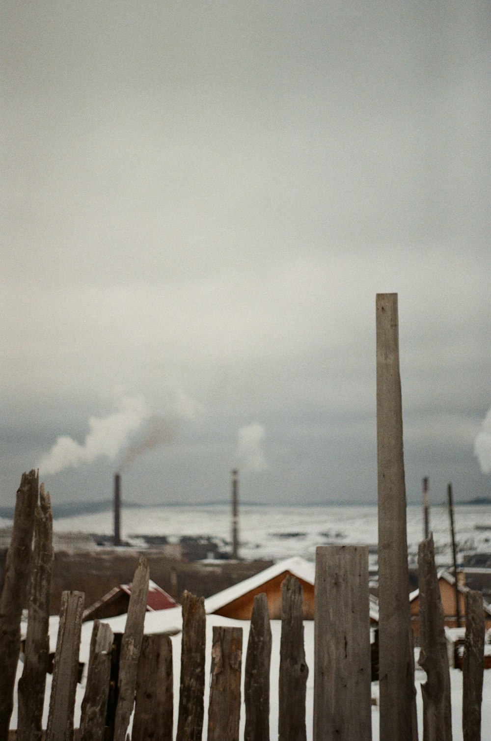 brown wooden fence near brown wooden house under white clouds during daytime