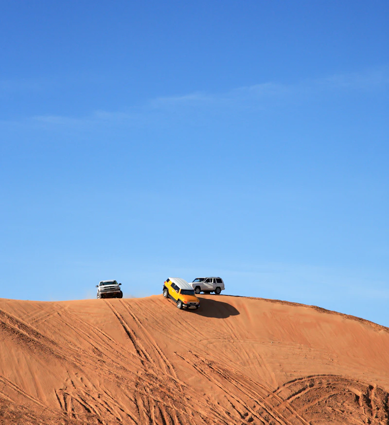 4x4 vehicles cresting a red sand dune in Ras Al Khaimah