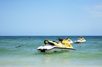 A group of friends laughing and riding jet skis under a bright sunny sky.