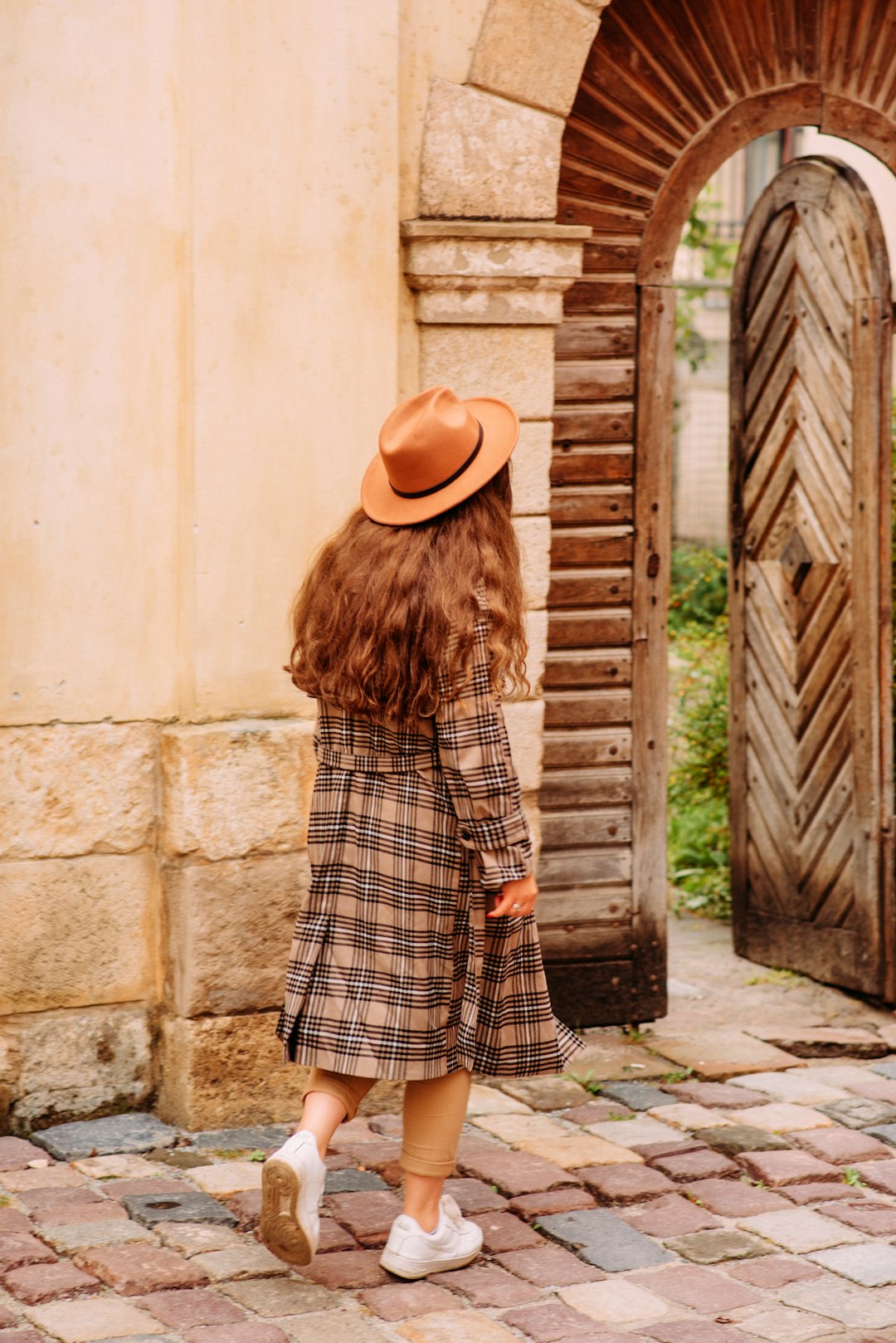 woman in black and white plaid dress wearing brown cowboy hat standing near brown wooden door