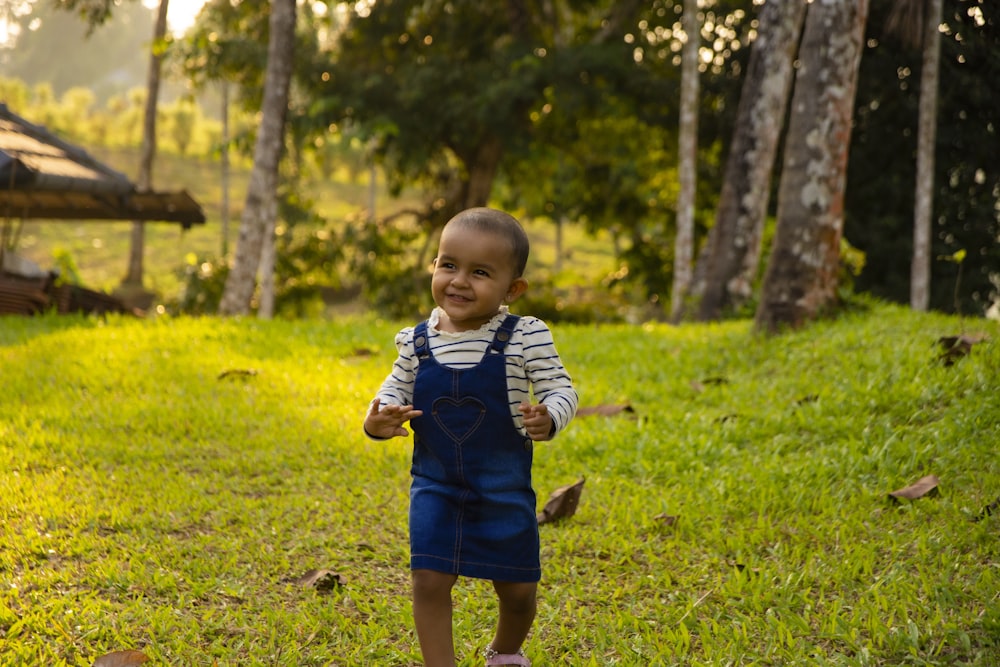 boy in blue and white striped long sleeve shirt standing on green grass field during daytime