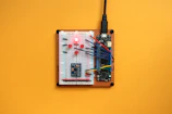 Hands assembling an Arduino-based IoT device with neon cyan accents.