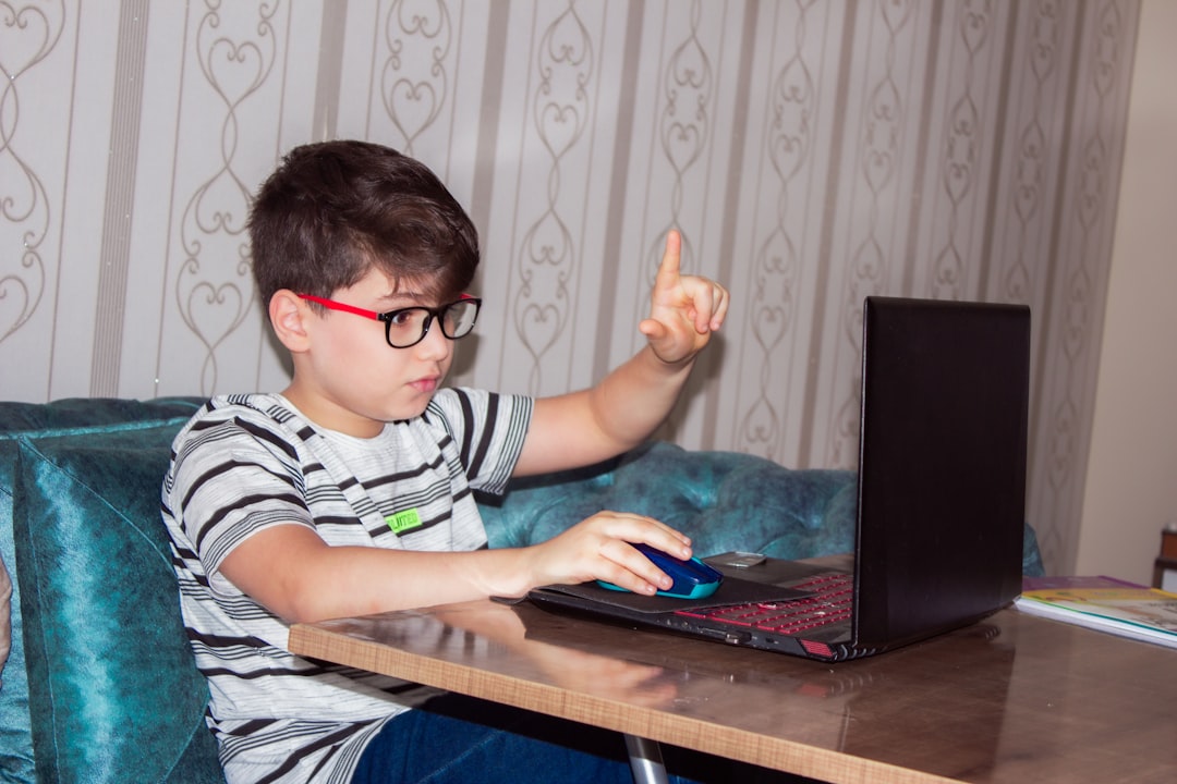 man in black and white stripe shirt using black laptop computer, A child receives distance education via the Internet be