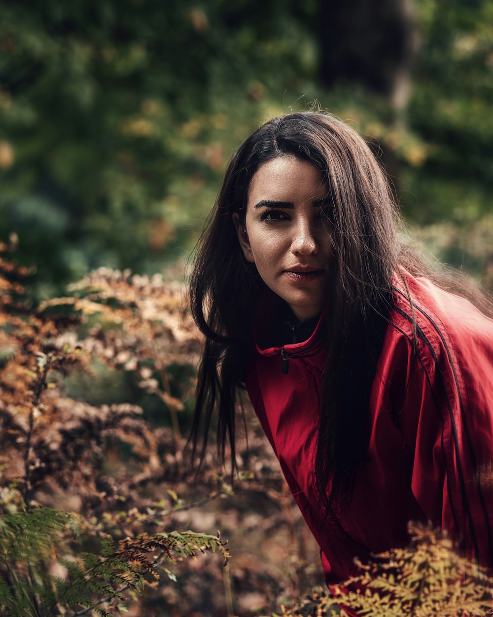 woman in red jacket standing near green plants during daytime