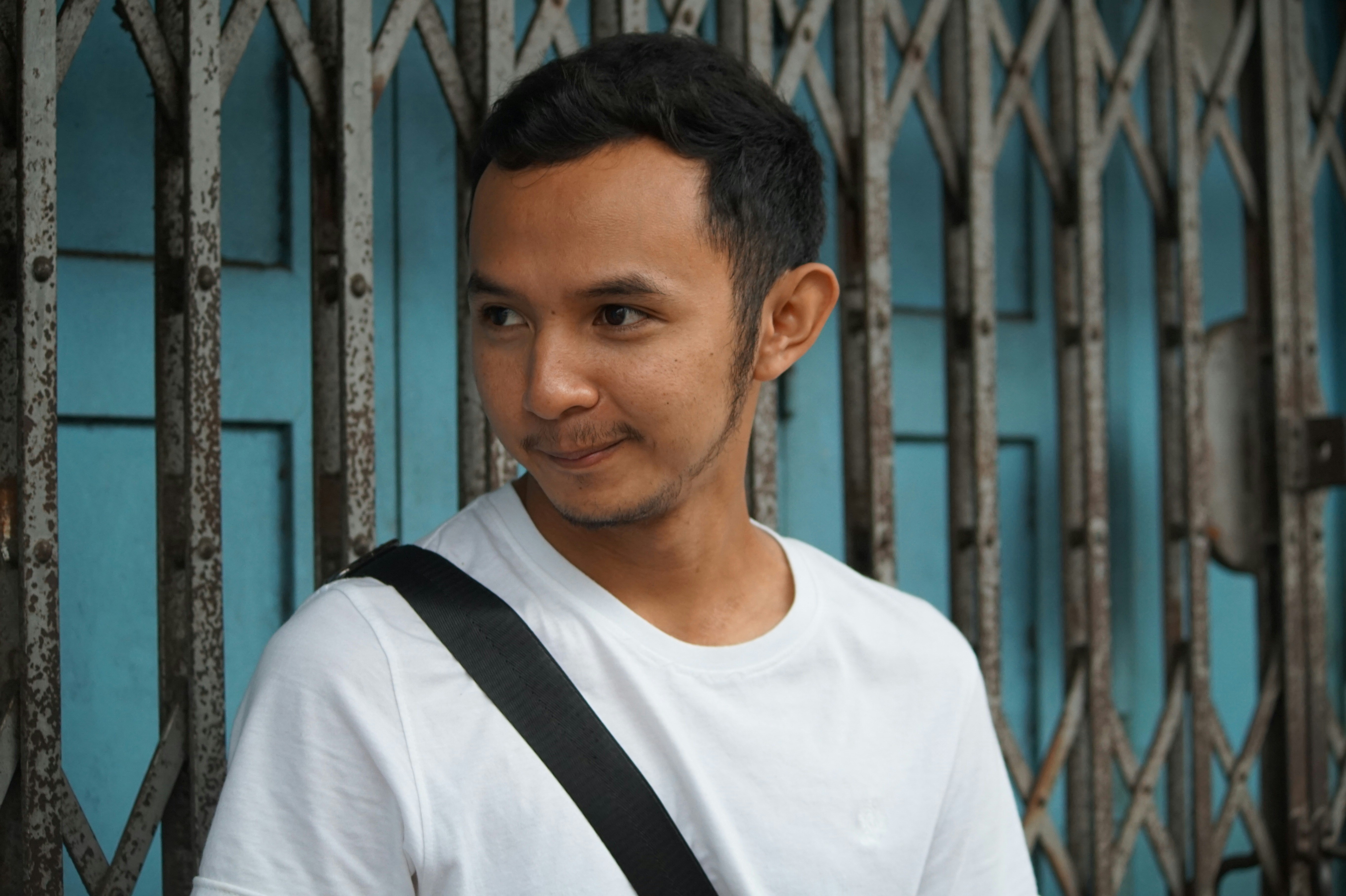 A man in white shirt with black slingbag is looking to another direction