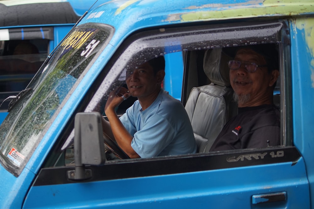 man in white button up shirt sitting on blue car