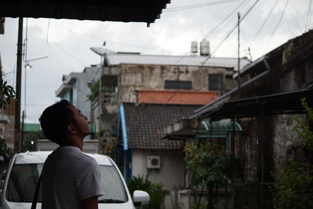 man in white shirt standing near white car during daytime