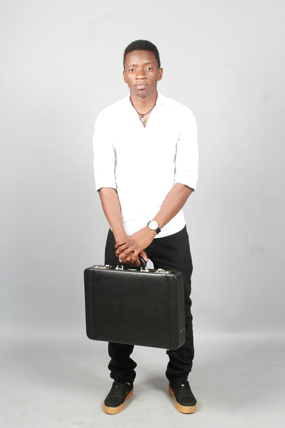 man in white button up shirt holding black leather suitcase