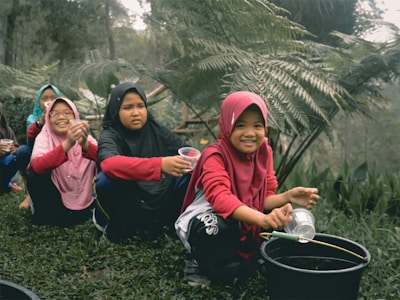 woman in red hoodie and black pants sitting beside girl in pink hoodie