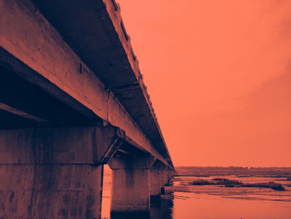 gray concrete bridge over the sea during sunset