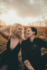 A candid shot of a couple laughing together in a golden hour sun-drenched field.