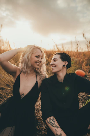 A candid shot of a couple laughing together in a golden hour sun-drenched field.