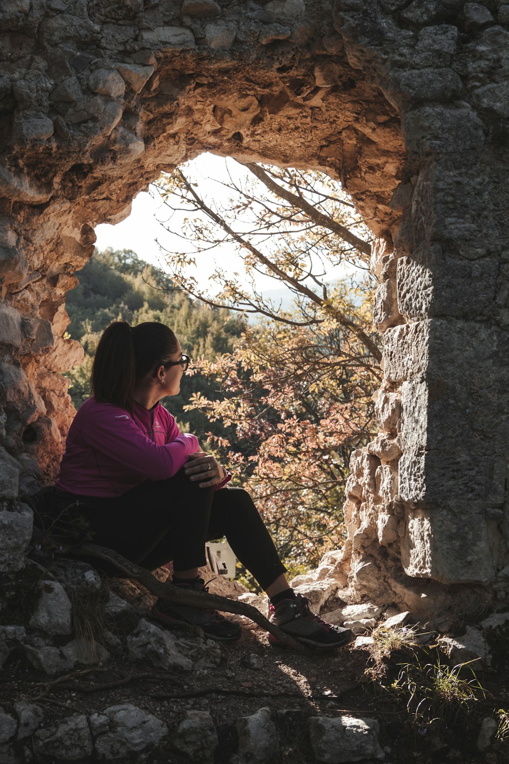 woman in purple long sleeve shirt sitting on rock during daytime